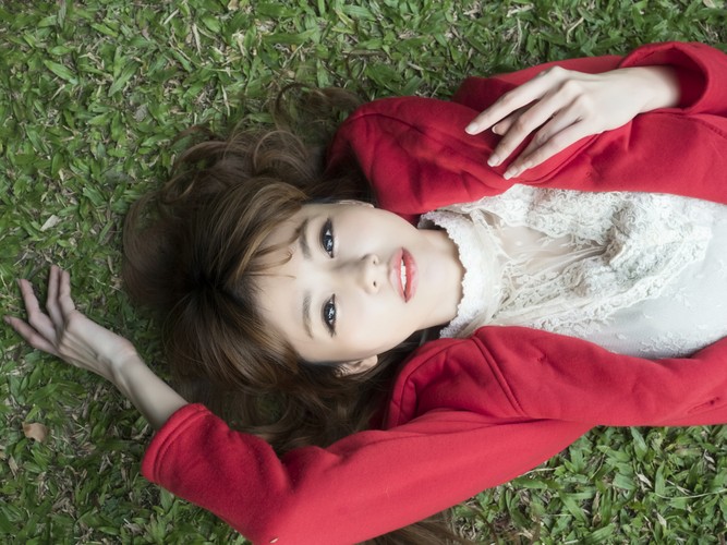 女人穿白衬衫穿红色夹克躺在碧绿的草地上