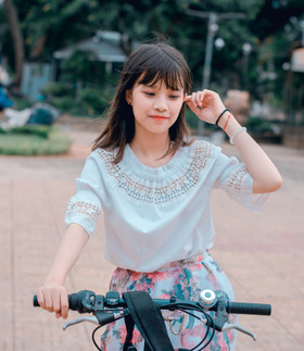 穿着白衬衫和五彩花裙骑自行车的女人